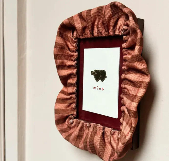 picture frame with red striped ruffled border framing red mount and picture