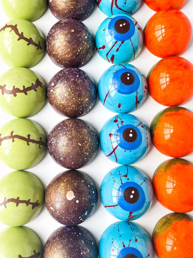 several colourful halloween chocolate balls are arranged on a white surface