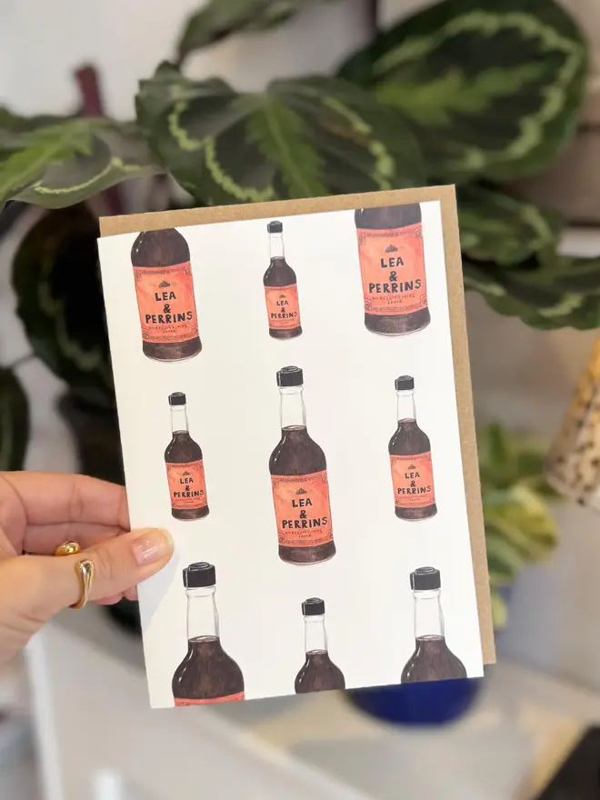 worcestershire sauce bottles illustrated card. card photographed with houseplants in background.