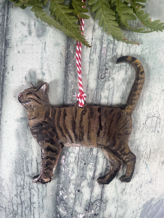 Tabby Cat Christmas Decoration with red and white twine placed onto a book about cats 