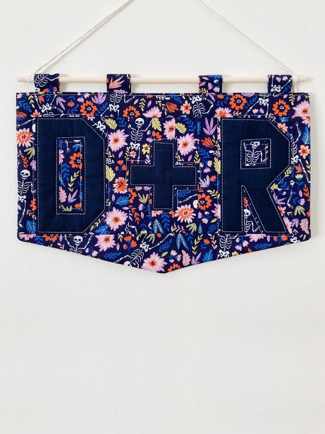 Personalised quilted double letter wall-hanging by Cooper and Fred with a blue floral pattern and blue lettering.