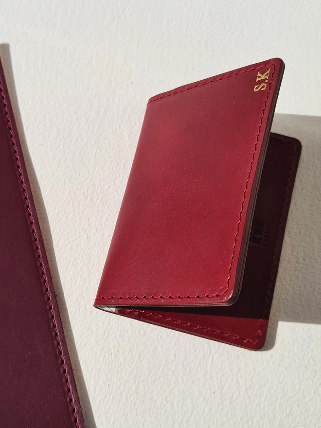 a red vegetable tanned leather cardholder lined with an original silk map from the Cold War and personalised with gold initials