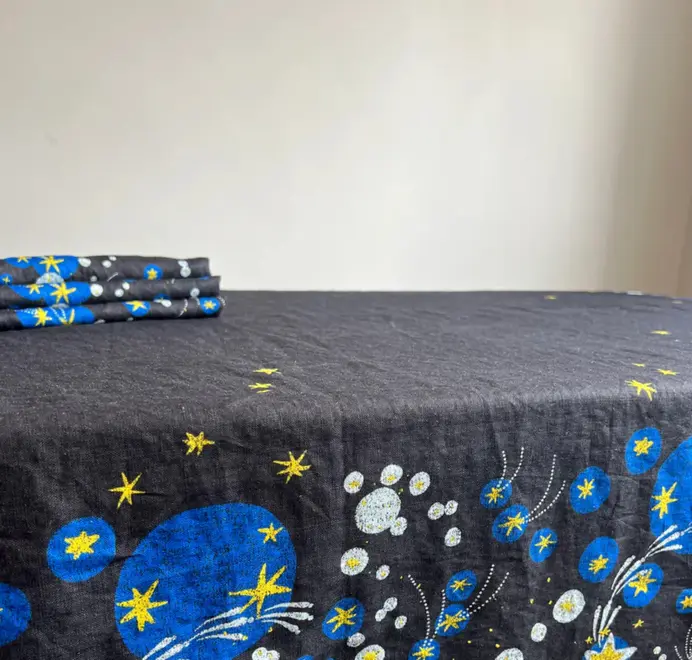 Solaris Napkins In White Or Blue. Blue cloth napkin with blue and yellow starburst and orbital patterns. 
