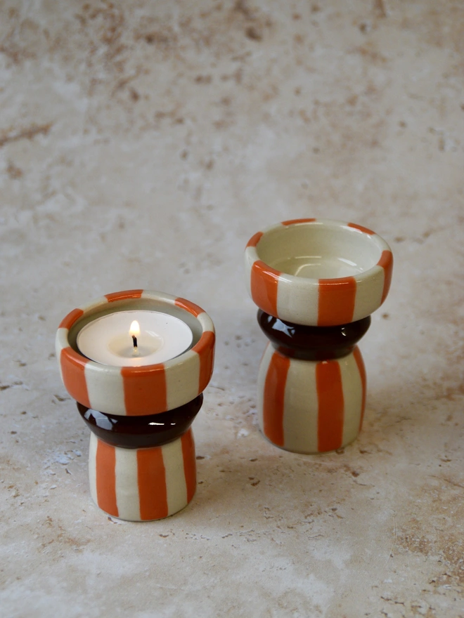Pair of handmade striped ceramic candlestick holders in orange and cream tones