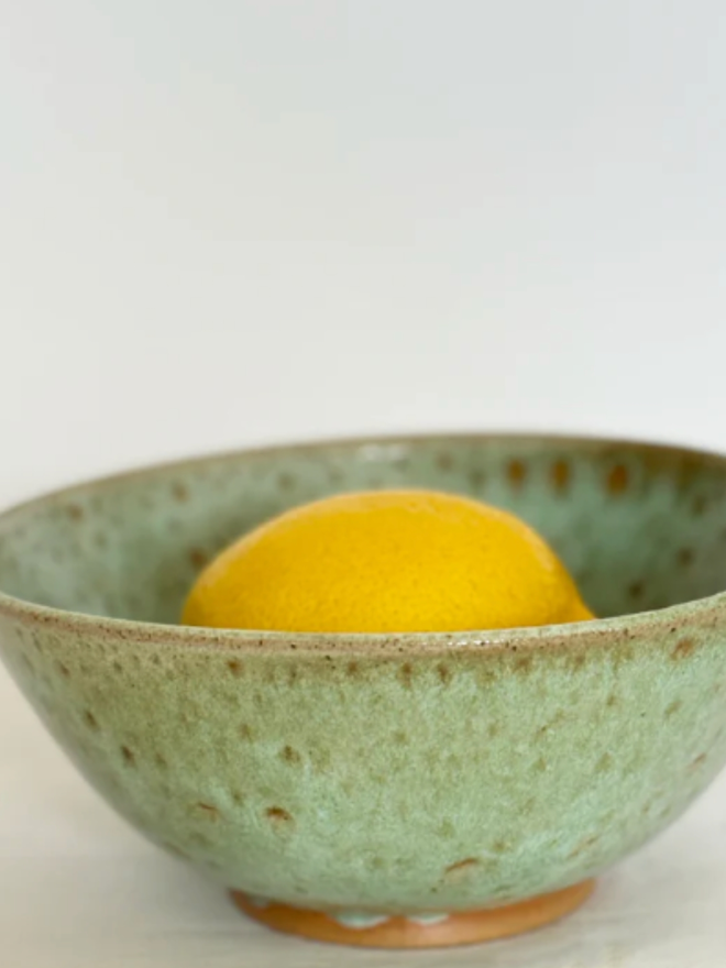 Cereal Bowl. A close up of a Green Cereal Bowl containing a lemon.