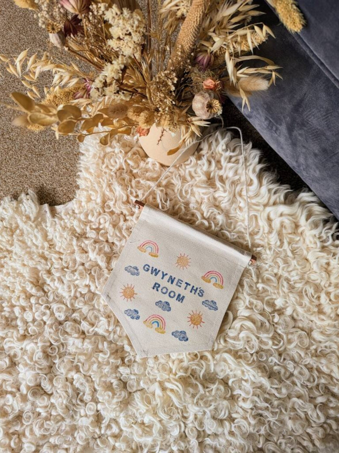 customised kids' bedroom cotton wall hanging. a banner with printed suns and rainbows hanging on a bedroom wall.