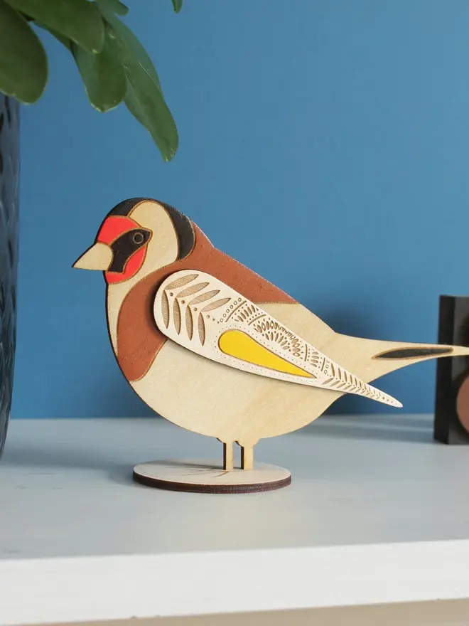 Standing Wooden Goldfinch, wooden bird decoration standing on a platform. 