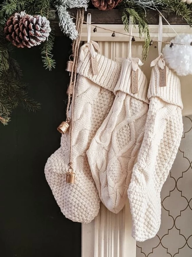 knitted stockings hung from a fireplace with ceramic name tags tied on