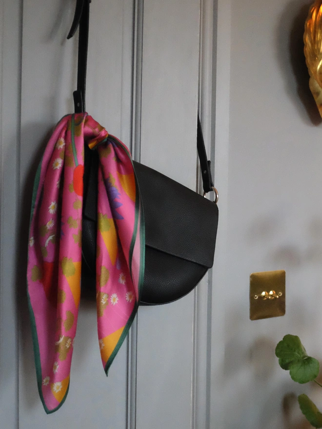 'In Bloom' Silk Scarf hanging on a leather handbag on a doorframe