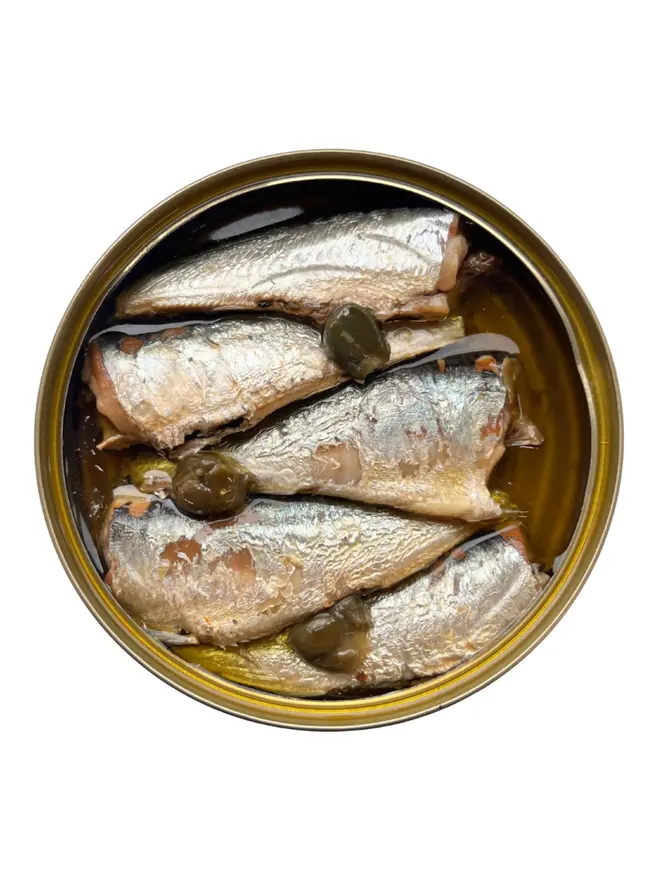 An open tin of Sea Sisters Cornish Sardines with Rosemary and Capers on a white background
