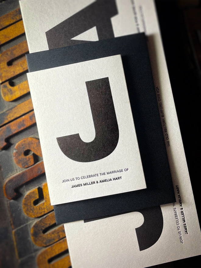 Close-up of Amour Mono personalised Save the Date with bold black typography, matching black envelope and tactile letterpress impression on luxury white card.