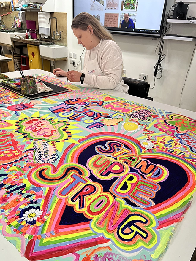 Artist working on full of joy original artwork for 100% organic cotton charity tea towel 