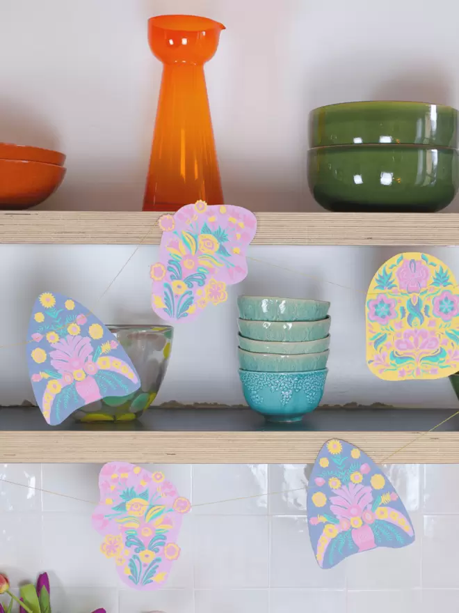 Pastel shapes on with vibrant glass vases and bowls on shelves
