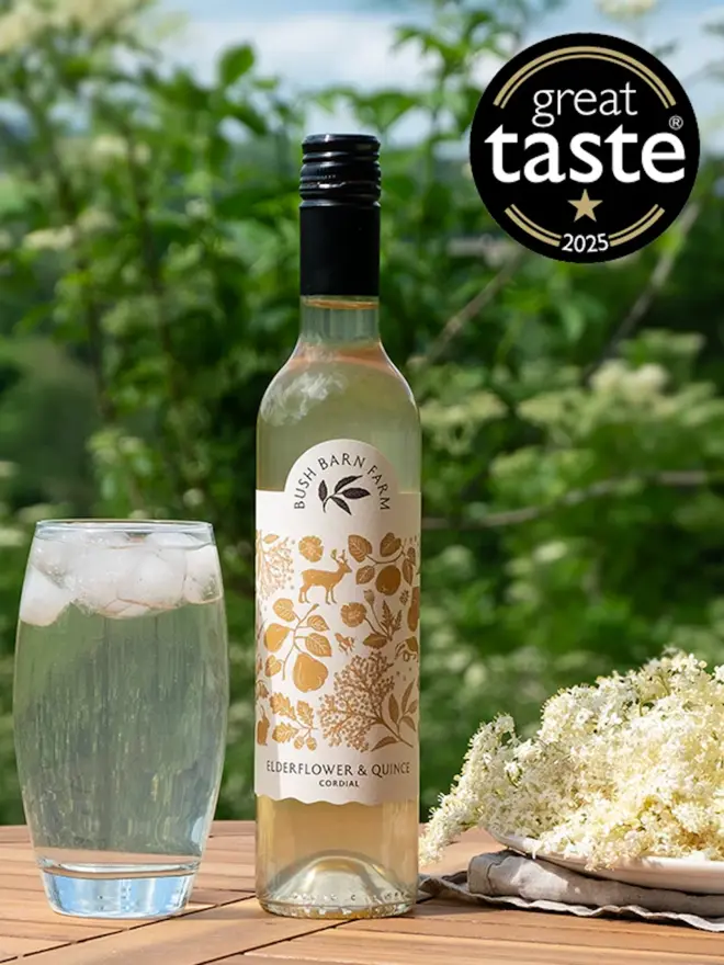 Elderflower & Quince Cordial (Set Of 1, 2, 3 Or 4), a glass of elderflower sitting next to a bottle of elderflower on a wooden table. 