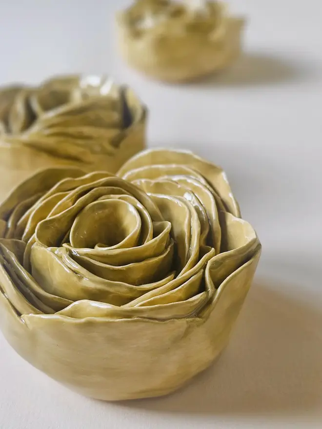 Handmade ceramic rose sculpture with a olive green glossy glaze, crafted in 3D and designed to hang on a wall