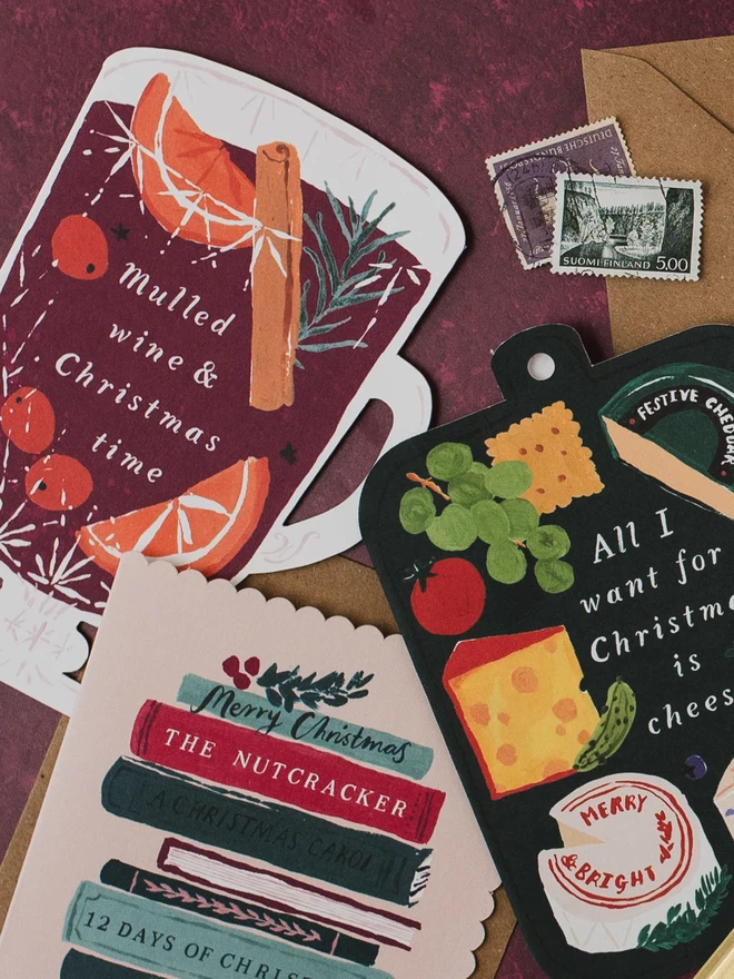 Mulled Wine Christmas card on a burgundy background with the Bookish and Cheeseboard Christmas cards and vintage stamps