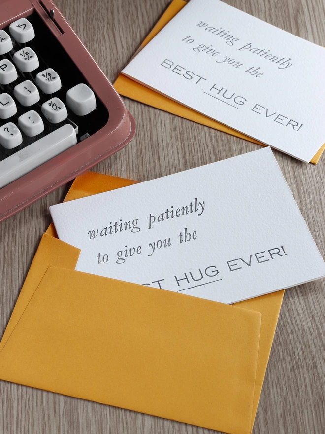 notecard with the text 'waiting patiently to give you the best hug ever' printed on the front with a mustard yellow envelope