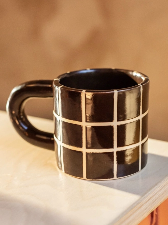 Grid Chunky Mug, a colourful mug with a grid pattern on a white table top surface. 