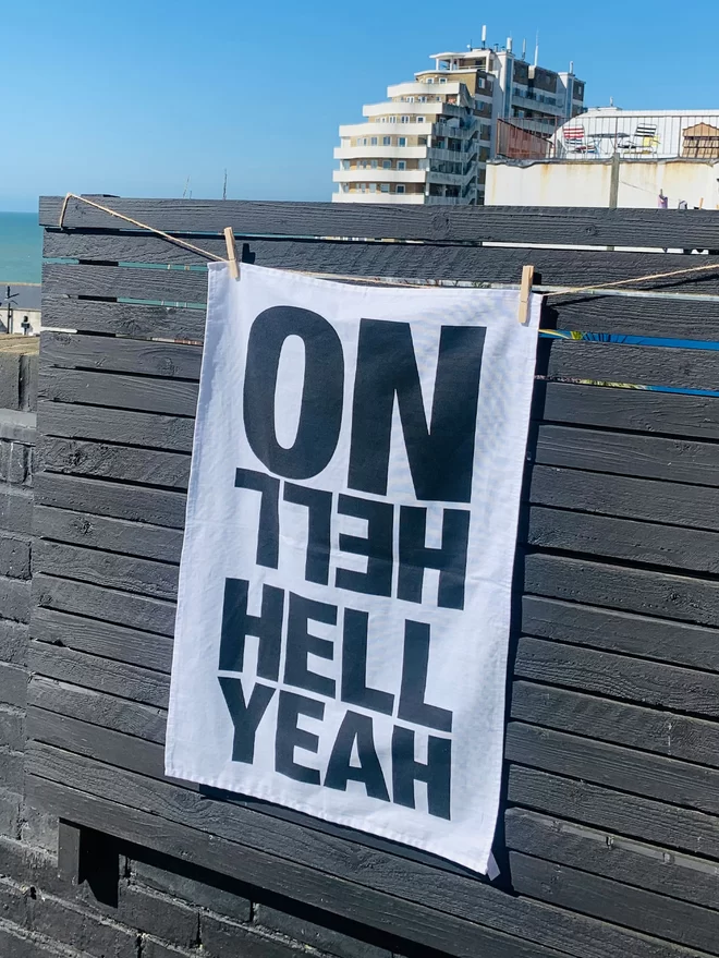 Hell Yeah Hell No screenprinted black text on white tea towel hanging on timber wall by the seaside
