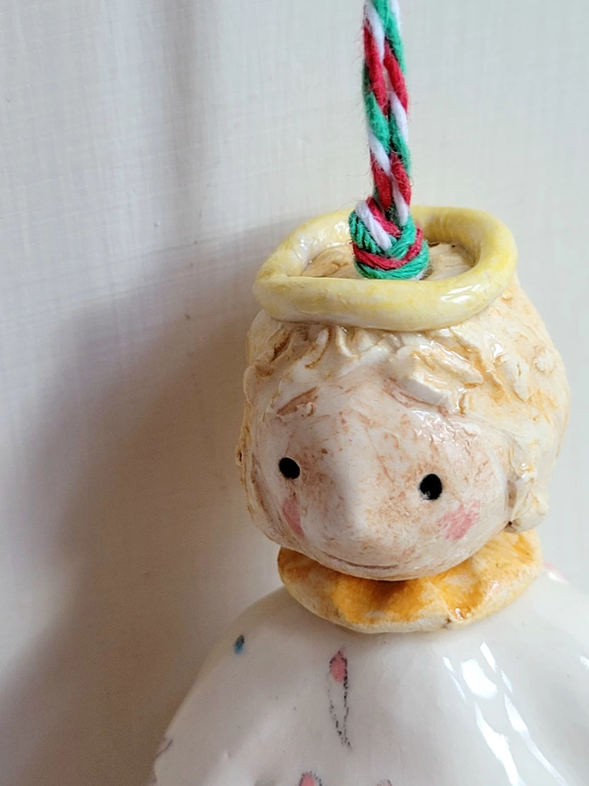 close up face of a pottery angel with hanging twine and yellow halo