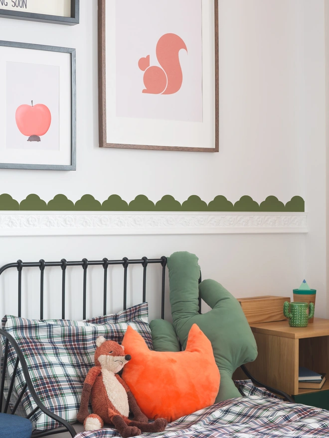 Temple scallp in Forest Green as a border behind a bed on a white wall with pictures above