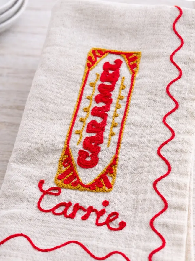 Personalised Hand-Embroidered Tunnocks napkin with 'Carrie' in red embroidery