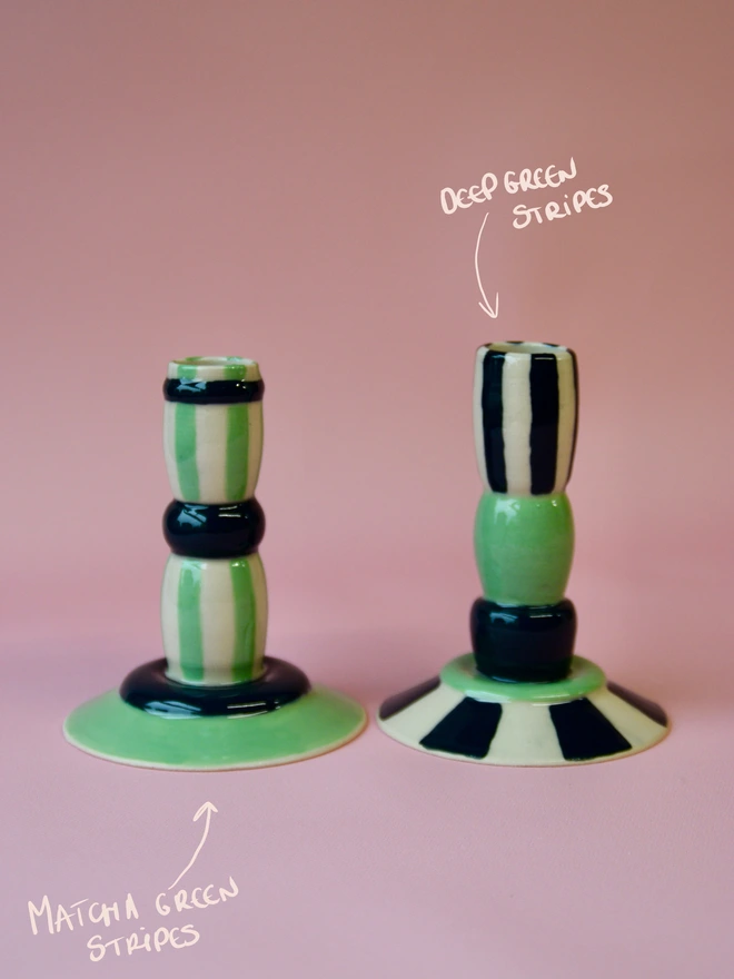 Handmade ceramic candlesticks with green stripe patterns, featuring matcha green stripes on the left and deep green striped design on the right, displayed on a soft pink background.