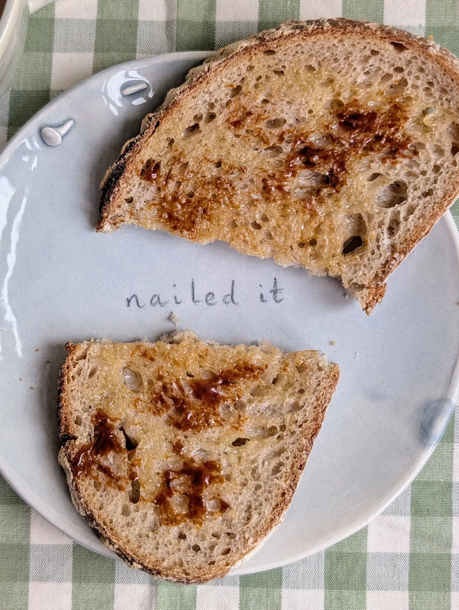 Nailed it plate with ceramic nail and grey translucent glaze with a piece of marmite on toast