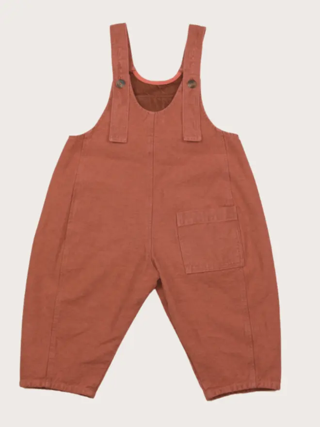 AW25 Kai oversized denim dungarees in coral overdye with curved seams and adjustable straps