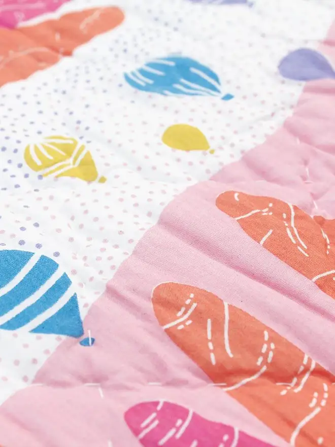 Fairy Chimney Quilt, a pink and yellow quilt sitting on a bed in a bedroom. 