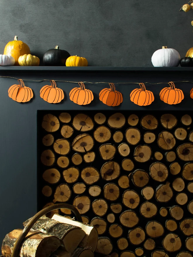 Orange paper pumpkin garland strung across black mantelpiece. 