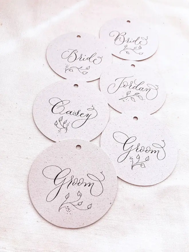 circular calligraphy wedding place cards. white circular place card with black calligraphy.