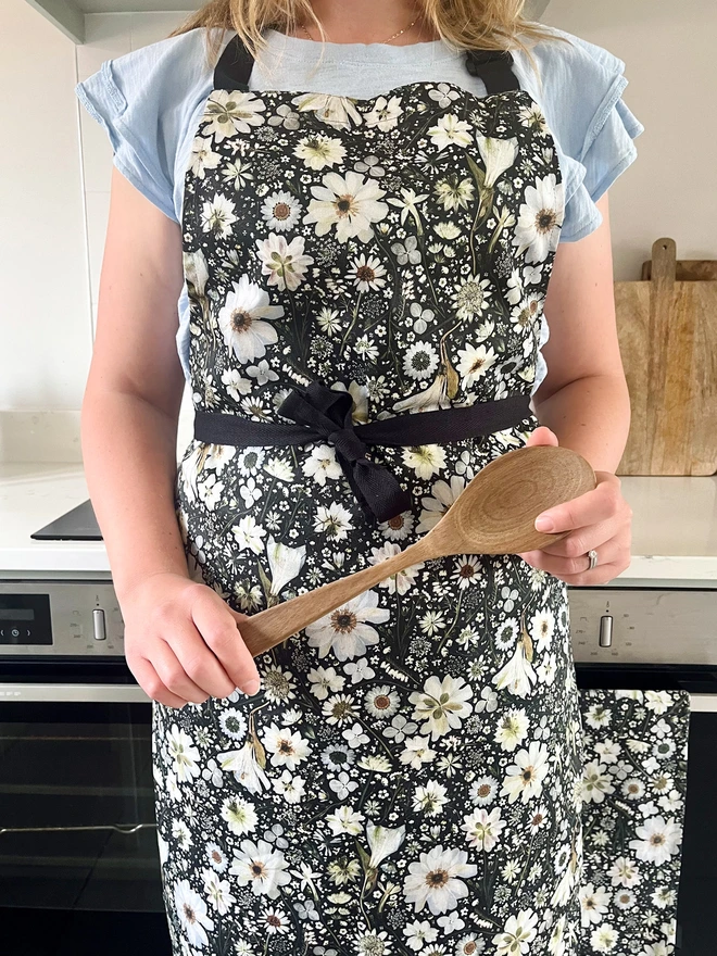 Botanical apron with a pressed flower design in black and white, with adjustable neck.