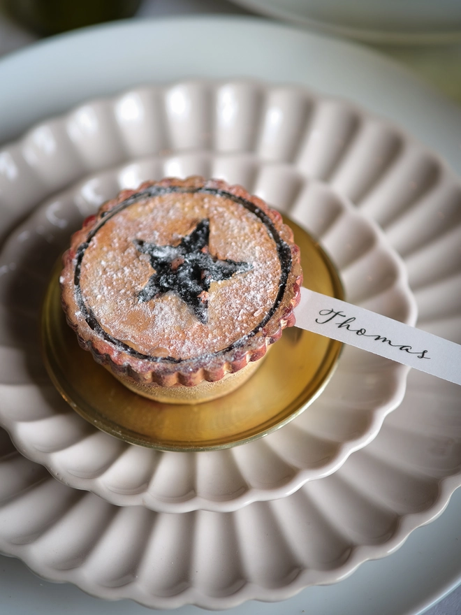 A festive handpainted wooden mince pie place setting with handwriten note to welcome your guests at the Christmas table