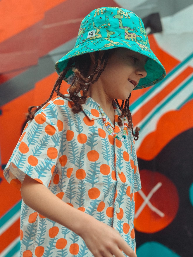 Boy wearing sun bucket hat reversible in Giraffe print