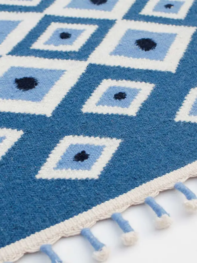Evil Eye Flatweave Rug, a colourful rug on a plain surface. 