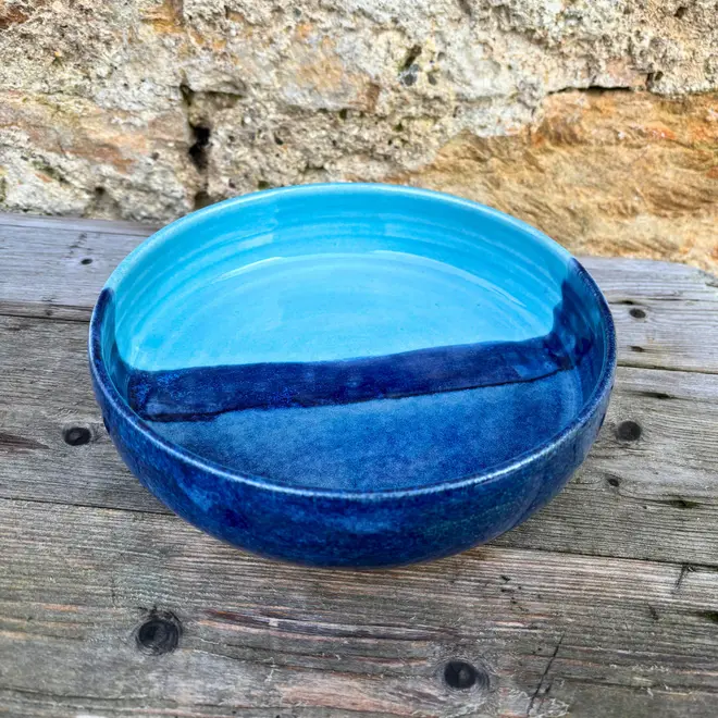 Landscape Pasta Bowl, a colourful pasta bowl on a wooden surface against a brick backdrop. 