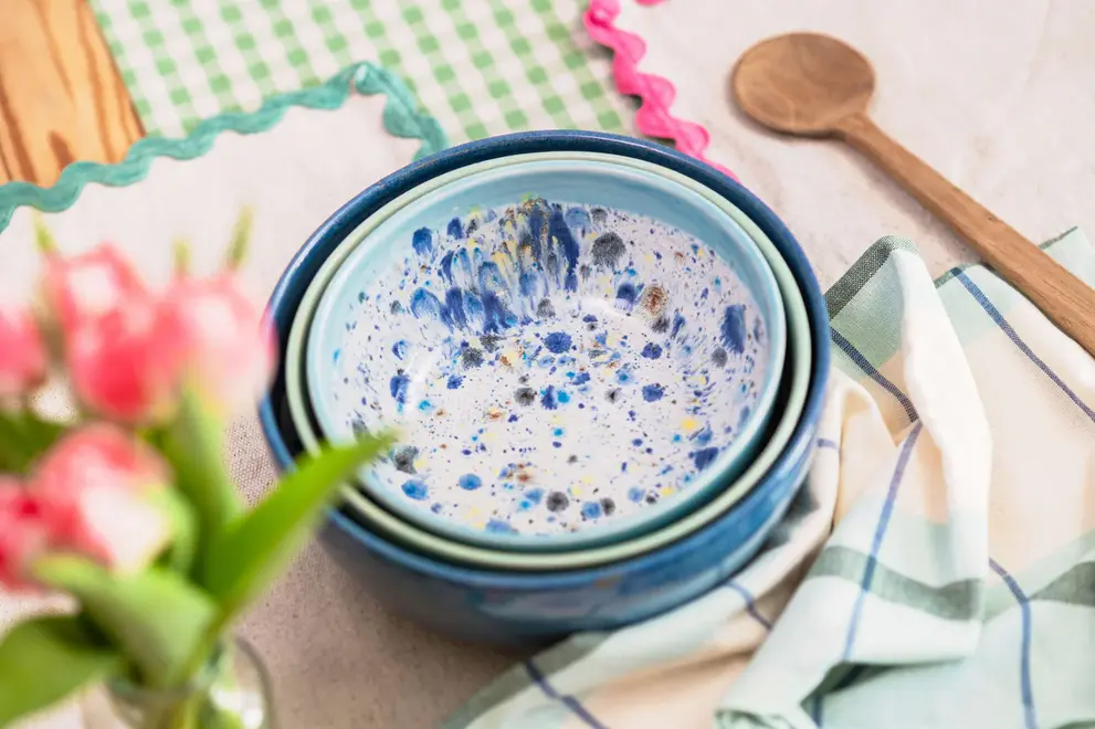Shoreline Serving Bowls (Set Of 3), a colourful set of serving bowls placed in a table setting accompanied by other kitchen items. 