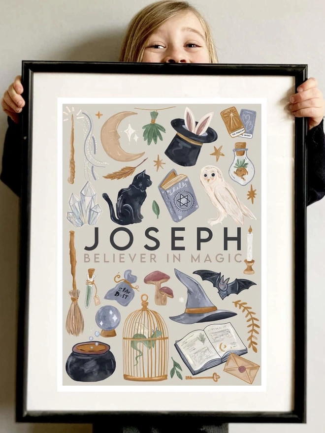 'Believer In Magic' Personalised Art Print, a child holding up the print against a white backdrop. 