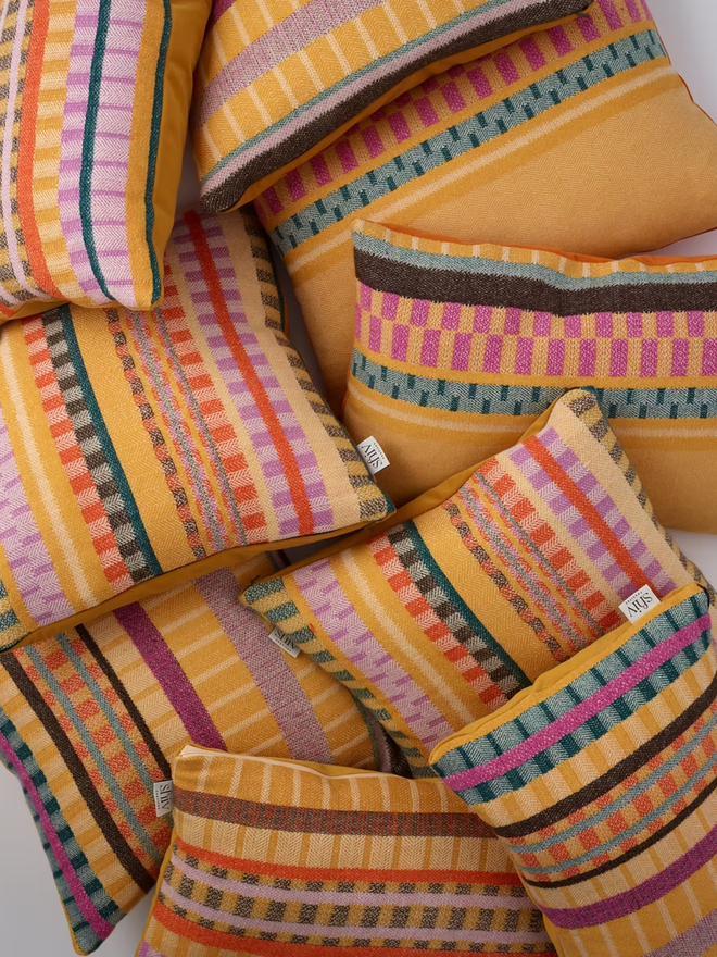 aoife square cushion. a pile multi coloured patterned square cushions.