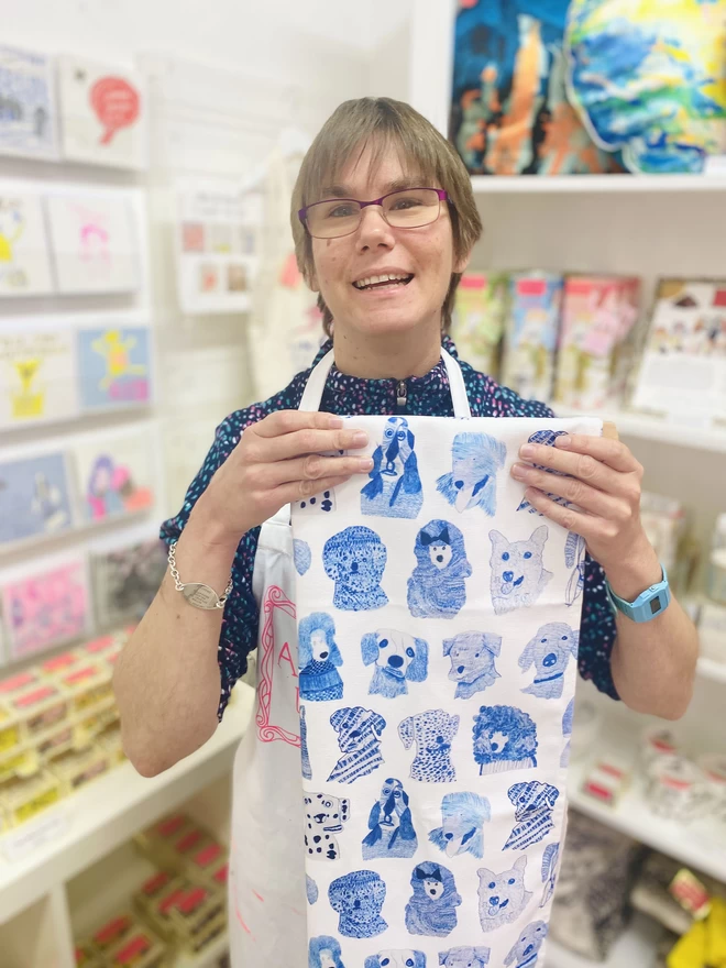 Happy artist holding blue dogs 100% organic cotton charity tea towel illustrated with blue sketched dogs