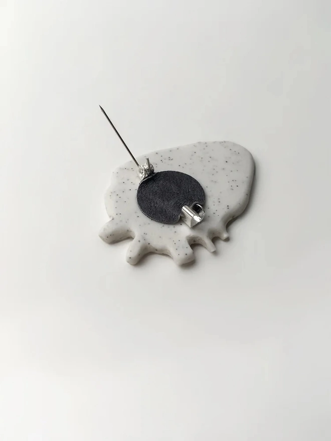 (Un)Broken Heart Pin, a white and gold heart pin sitting on a white surface. 