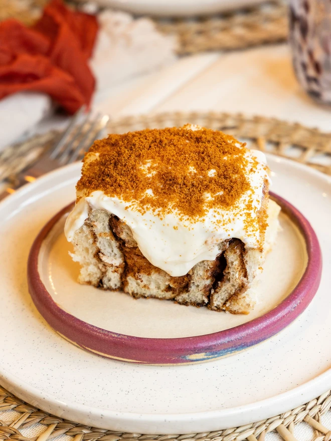 Buns of Joy Biscoff Cinnamon bun on a pink plate with vanilla frosting