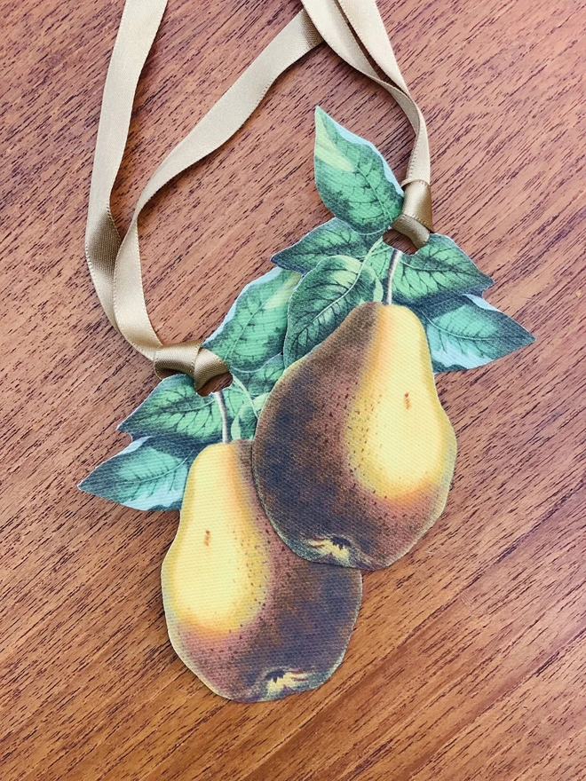 A pair of festive napkin ties in the shape of a golden pear with satin ribbons