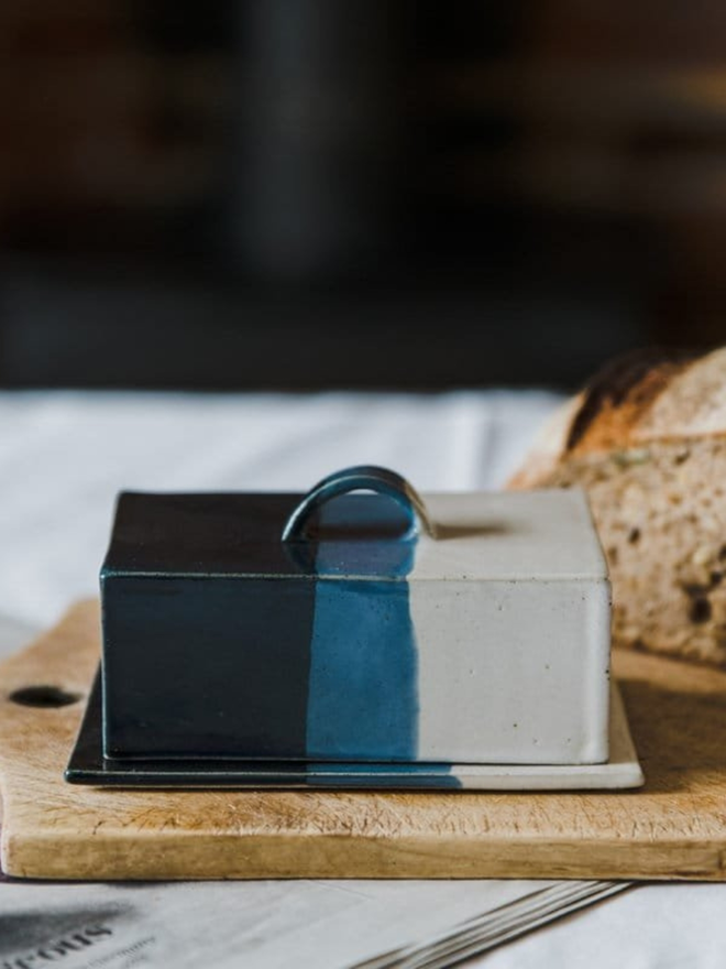 blue and white handmade butter dish on board with sourdough