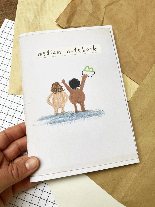 hand holding notebook with illustration of swimmers on the cover