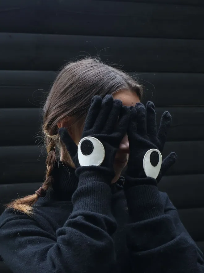 Googly eye iron on patches on black gloves hiding face