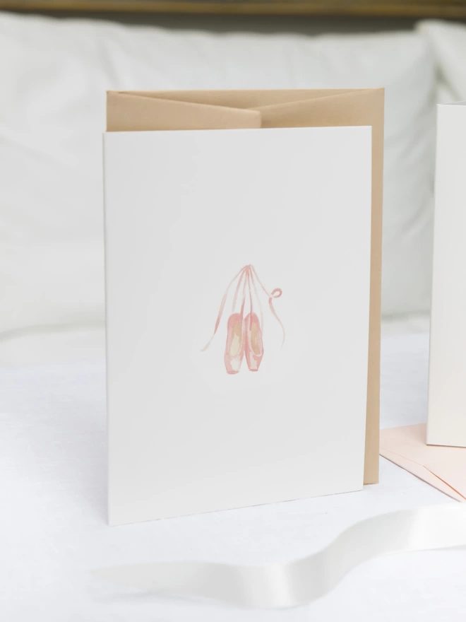 Greetings card with a watercolour illustration of a pair of ballet shoes with an oat coloured envelope