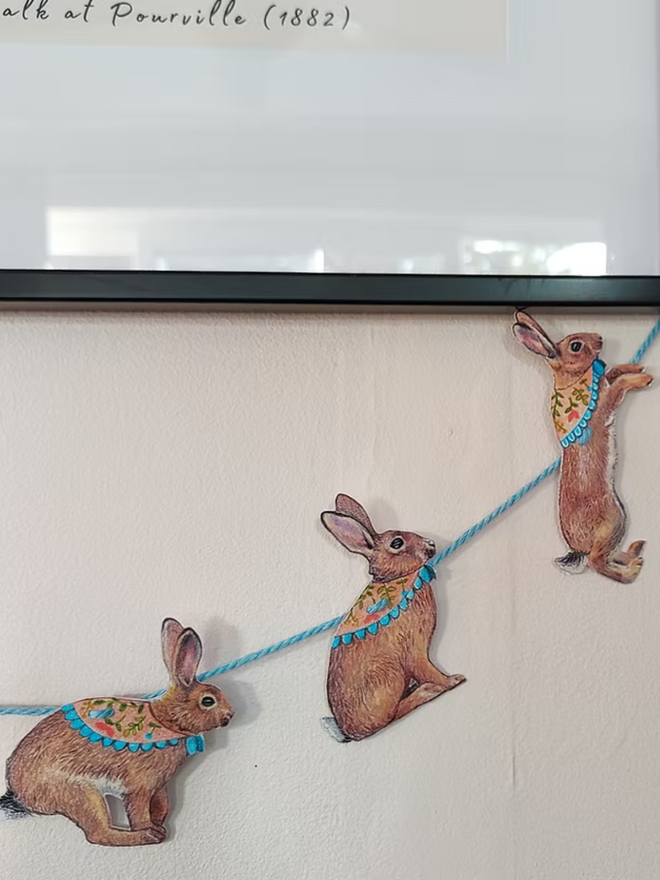illustrated easter bunny garland. bunnies with easter scarves on bunting hung on a wall.
