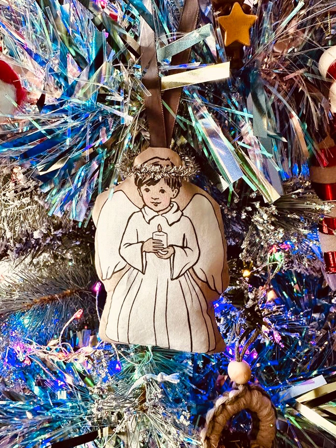 little angel christmas tree decoration, boy holding a candle nestled into a tinsel tree